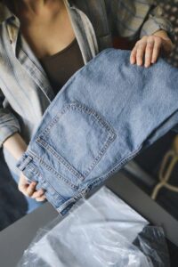 A person holding folded denim jeans