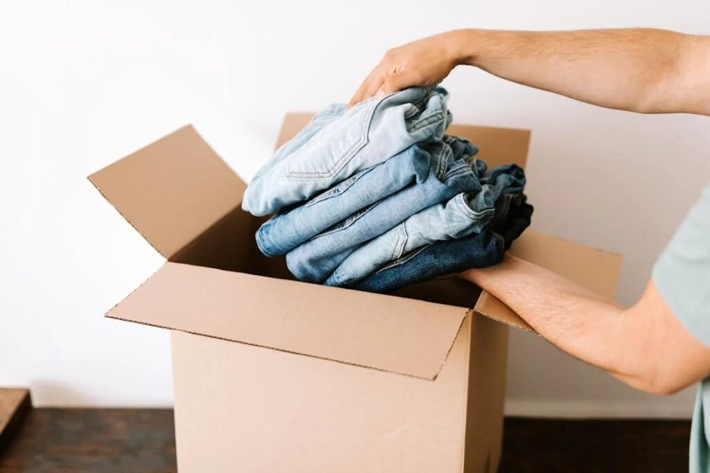 A person putting jeans in a box